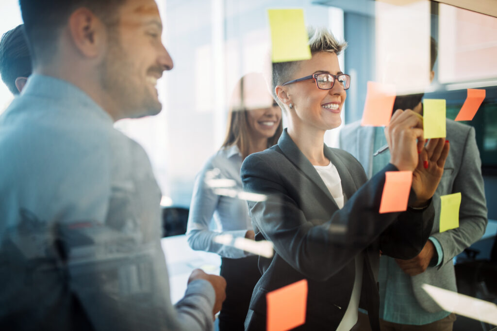 a person writing on sticky notes and collaborating with a team 